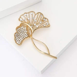 Elegant gold ginkgo leaf brooch with sparkling crystals on a modern white background
