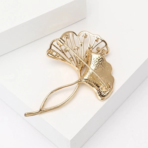 Detail showing the hammered texture and safety pin clasp of a golden ginkgo leaf brooch