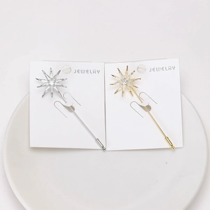 Detailed view of silver and gold star brooches with cubic zirconia on display card