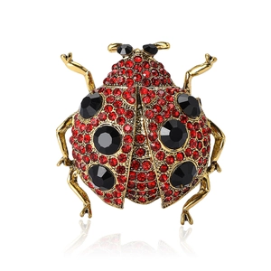 Broche coccinelle dorée à la mode avec cristaux rouges et pierres noires sur fond blanc