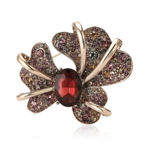 Vintage gold fleur-de-lis brooch featuring a large red gemstone and colorful crystals