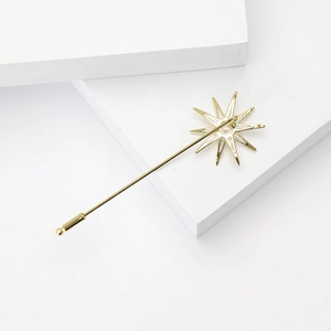 Detail of a gold eight-pointed star brooch with cubic zirconia on a minimalist white block