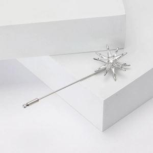 Detail of silver starburst brooch with cubic zirconia on white geometric stand