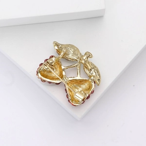 Dettaglio del retro di una spilla a fragola con chiusura dorata e strass scintillanti