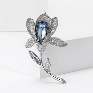 Macro detail of luxury lily brooch with silver metal and large pear-cut blue crystal