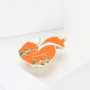 Simpatica spilla a forma di volpe in smalto arancio e bianco con accenti di foglie verdi