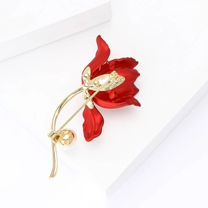 Elegant tulip flower brooch in red and gold finish with pearl detail on a white stand