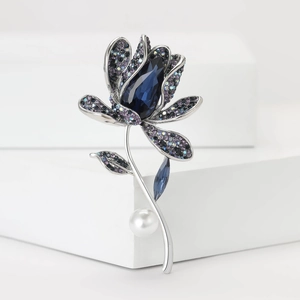 Macro detail of orchid brooch featuring blue teardrop crystal and rhinestone petals