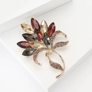 Elegant vintage flower brooch with amber crystals and rhinestones on a white pedestal