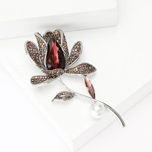 Elegant tulip brooch with red gemstone and pink crystals on a white pedestal