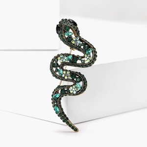 Détail de la broche serpent ornée de cristaux verts sur une base en métal doré rétro