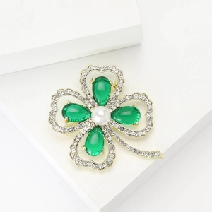 Elegante spilla a quadrifoglio dorata con cristalli verdi e perla su cubi bianchi