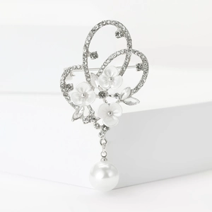 Détail macro d'une broche papillon argentée avec strass, fleurs blanches et perle