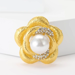 Élégante broche fleur en or mat avec perle blanche et strass sur un socle blanc