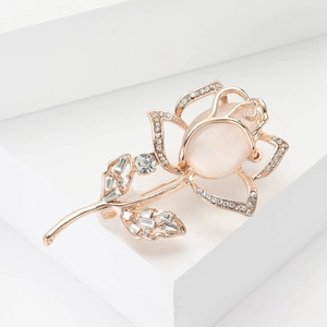 Rose gold tulip brooch with pink cat eye stone and sparkling crystals on white pedestal