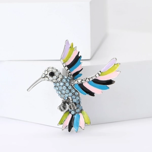 Détail d'une broche colibri avec ailes en émail coloré et cristaux étincelants