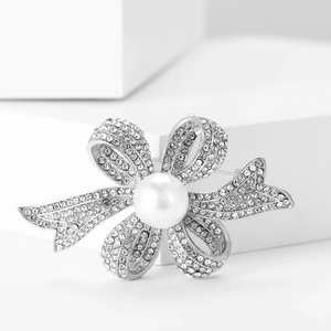 Détail de l'élégante broche nœud avec des strass étincelants et une perle blanche centrale