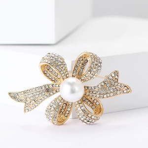 Élégante broche nœud dorée avec cristaux scintillants et une grande perle blanche
