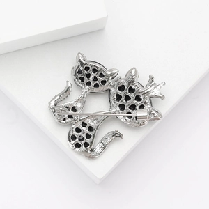 Back view of silver alloy cat brooch with heart cutouts and safety pin on white stand