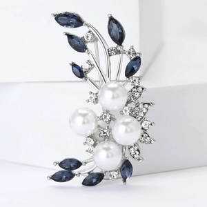 Elegant silver flower brooch with white pearls and blue rhinestones on a clean white base