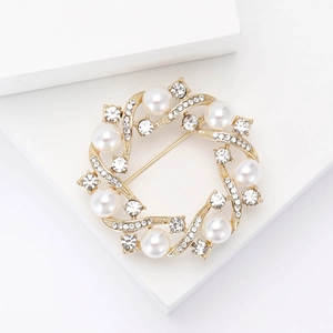 Elegant gold alloy wreath brooch with white pearls and sparkling crystals on white background
