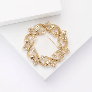 Detail view of a golden floral wreath brooch with white pearls and intricate metal carvings