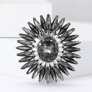 Dettaglio della spilla a girasole con strass grigio scuro e zirconi su blocco bianco