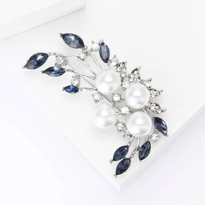 Elegant silver flower brooch with pearls and blue marquise crystals on white stand