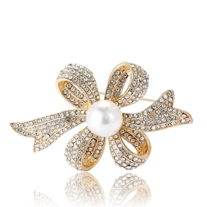 Broche nœud élégante dorée avec strass scintillants et une grande perle blanche