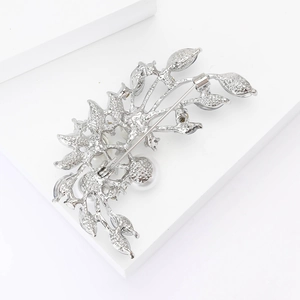 Detailed back view of a silver flower brooch featuring pin closure and pearl inlay