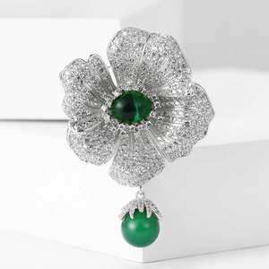 Macro shot of silver begonia flower brooch with green gemstones and zircon detailing