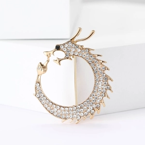 Detailed macro of golden dragon brooch featuring sparkling rhinestones on geometric stand