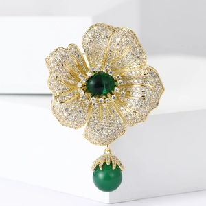 Luxury gold flower brooch with green stones and sparkling zircon pavé on white stand