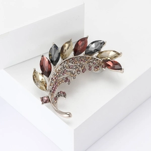 Élégante broche feuille argentée ornée de strass colorés sur un socle blanc