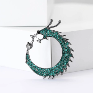 Detail of dragon brooch featuring green rhinestones and dark alloy metal texture