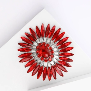 Dettaglio spilla a girasole con strass rossi vibranti e gemma centrale tipo rubino