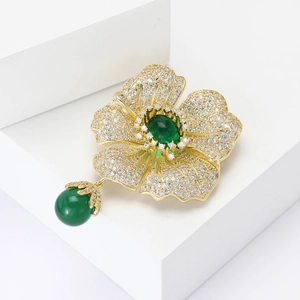 Elegant begonia flower brooch with green gemstones and pavé crystals on gold base