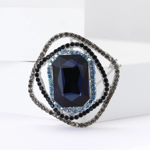 Macro shot of a vintage square brooch featuring a large navy blue gem and crystals