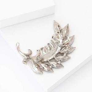 Vue arrière détaillée d'une broche feuille argentée avec motifs étoiles et épingle