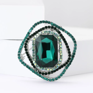 Macro shot of silver alloy brooch with emerald green crystal and pavé rhinestones