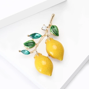 Double lemon brooch with yellow enamel fruits and green leaves on a white background