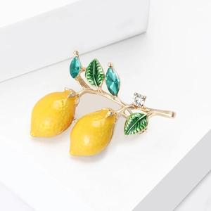 Elegant yellow enamel lemon brooch with green crystals on white stone pedestal