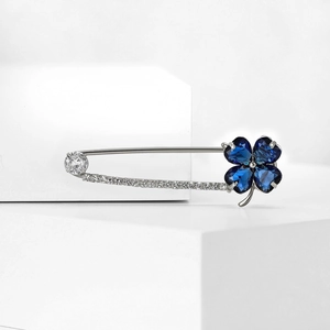 Détail macro d'une broche trèfle en argent avec cristaux bleus et zircons blancs étincelants