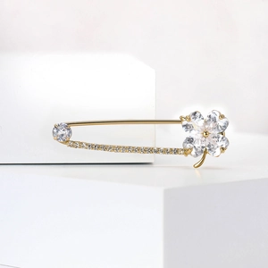 Détail macro d'une broche trèfle dorée ornée de zircons transparents en forme de cœur