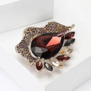 Fashion alloy brooch with red teardrop gem and colorful rhinestones on white stand