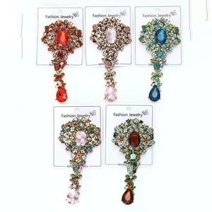 Dettaglio di spille stile palazzo vintage con strass colorati e ciondoli a goccia