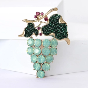 Dettaglio macro di spilla a uva in lega con strass verdi e cristalli azzurri
