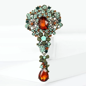 Dettaglio di una spilla in lega vintage con pietre ambrate e strass colorati brillanti