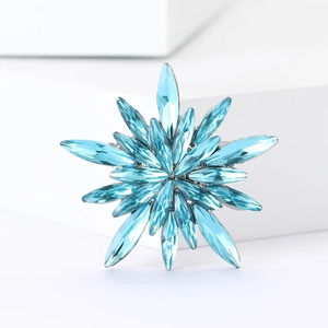 Star-shaped rhinestone brooch with blue crystals on white geometric display stand