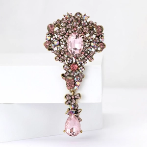 Vista macro della spilla in stile palazzo vintage con strass rosa e pendente a goccia